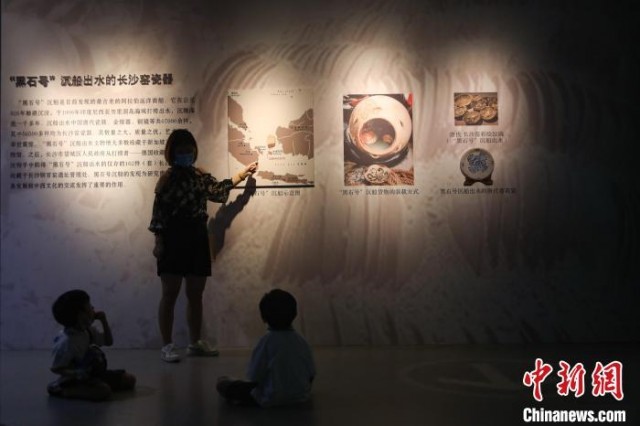 图为一位家长在给两位小朋友讲解墙上展板的内容。　刘力鑫 摄