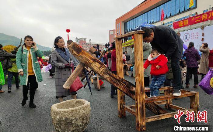广西灌阳"二月八"农具节上,游客在舂米碓上玩耍. 杨宗盛 摄